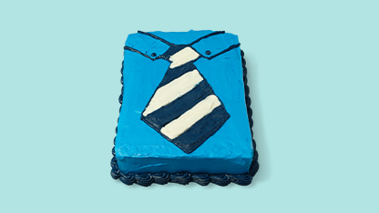 A square cake decorated to look like a blue tie, placed on a light blue background.